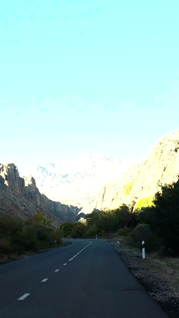 An empty road winding between rock formations in a mountain gorge