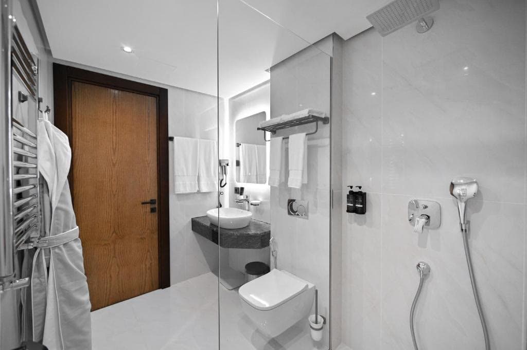 A white en-suite bathroom with a walk-in shower and robes on the rail