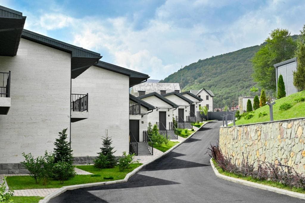 Resort villas along a landscaped drive with a forested hill behind
