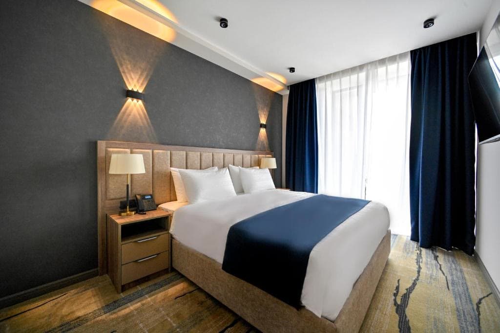 A hotel room with a large double bed, dark feature wall and wooden floor