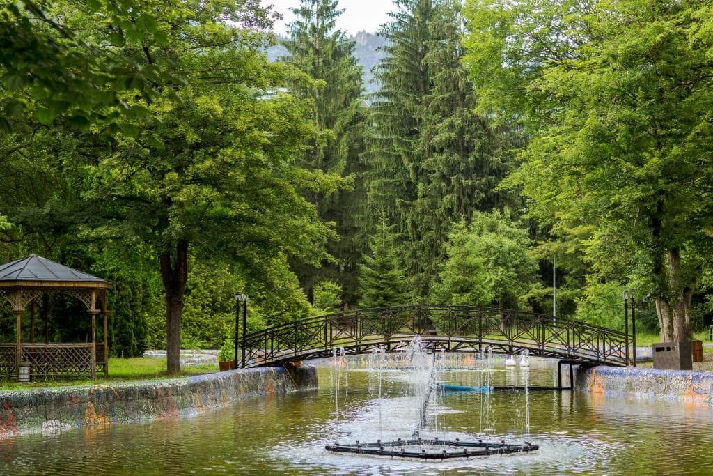 A footbridge and fountain among the tall trees of Borjomi park