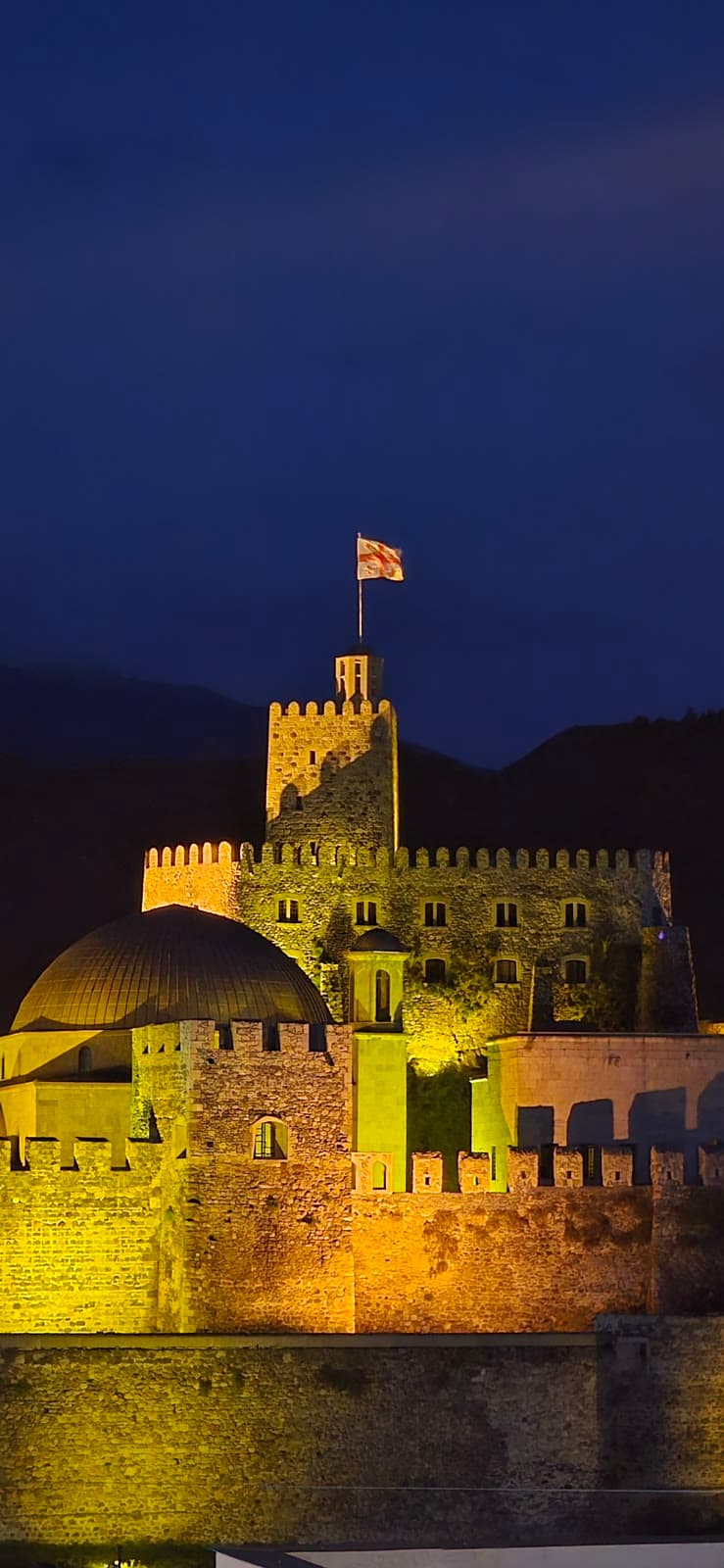 Rabati fortress lit gold against the night sky