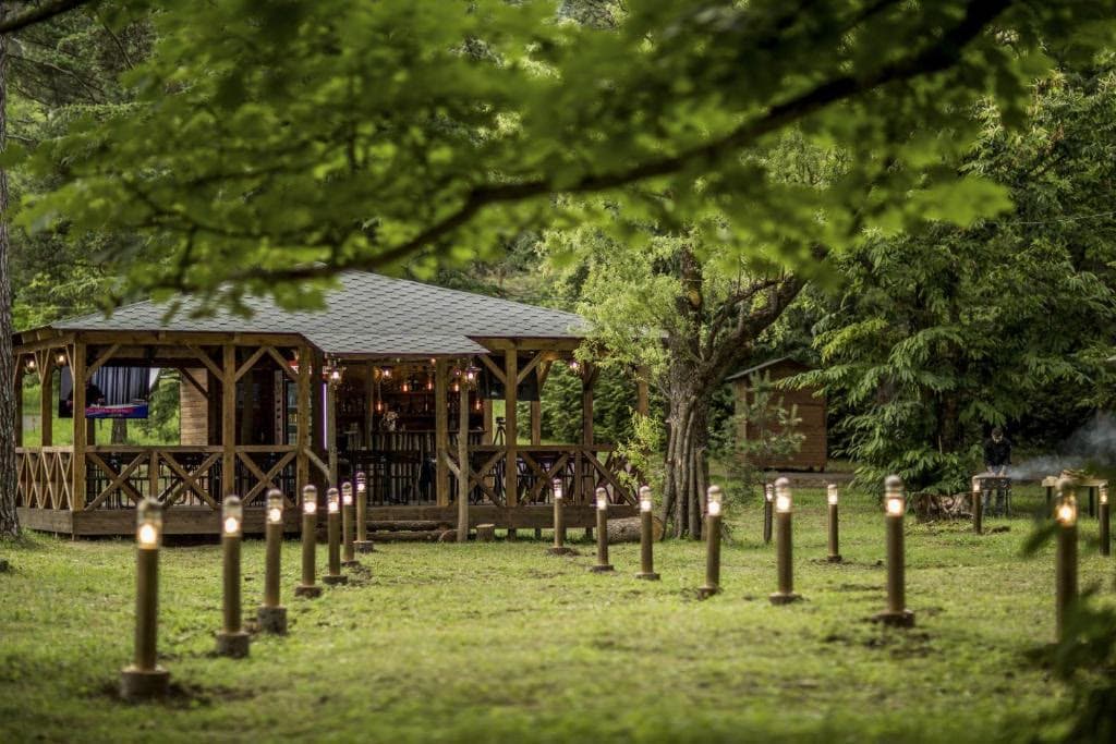 A wooden pavilion and lamplit path in the hotel gardens at dusk