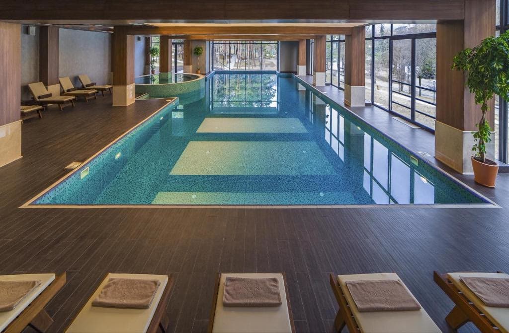 The indoor swimming pool, lined with loungers under a glazed roof