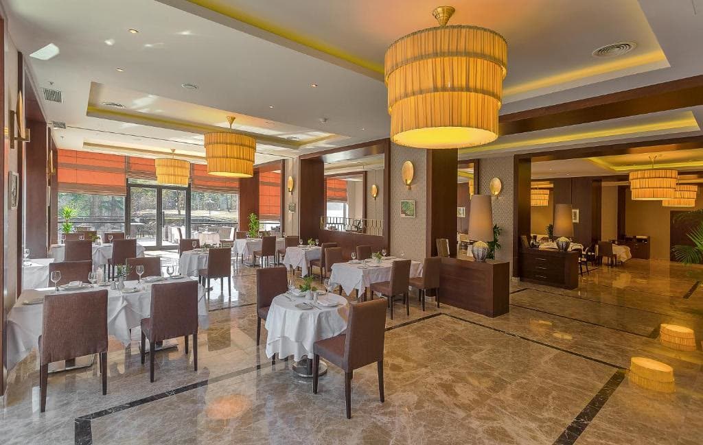 The hotel restaurant laid for dinner beneath a large pendant light