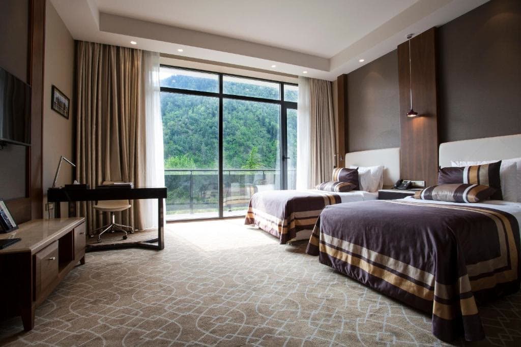 A twin room with two beds, a desk and a balcony window over the valley