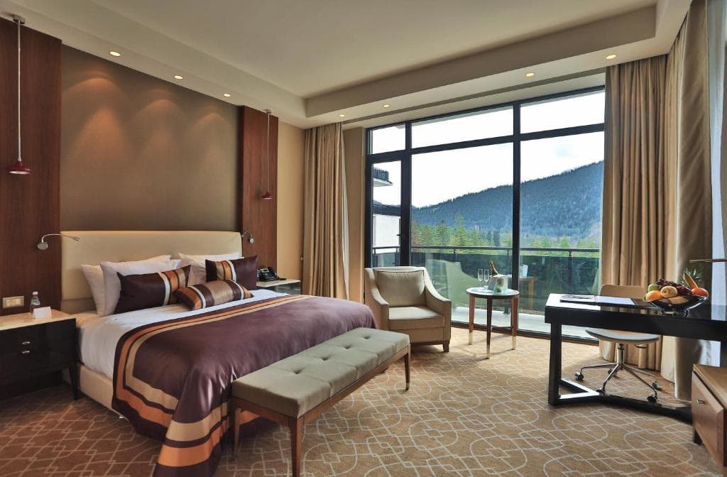 A single room with a wide window looking onto the forested hillside