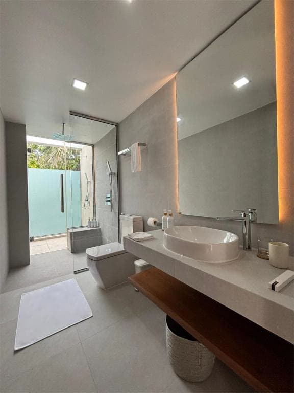 Twin basins on a dark wood vanity, with a door open to a planted outdoor space