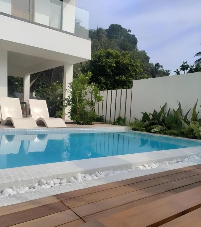 The villa's private pool and wooden deck, with sun loungers under a white balcony