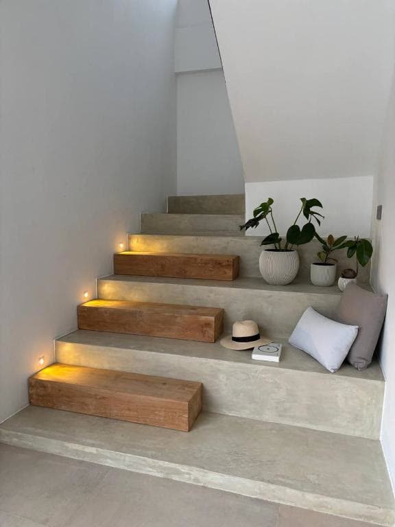A concrete and timber staircase lit at each tread, lined with potted plants