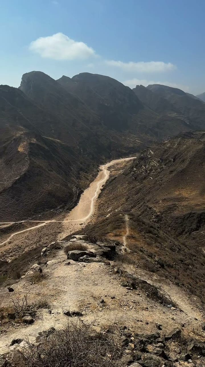 A road winding down through bare coastal mountains toward the sea
