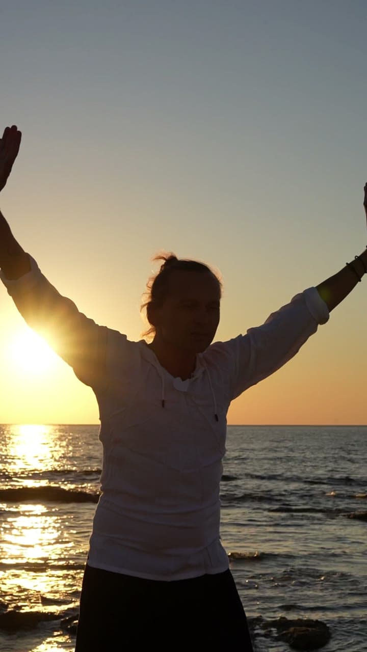 Standing breath practice by the sea at golden hour