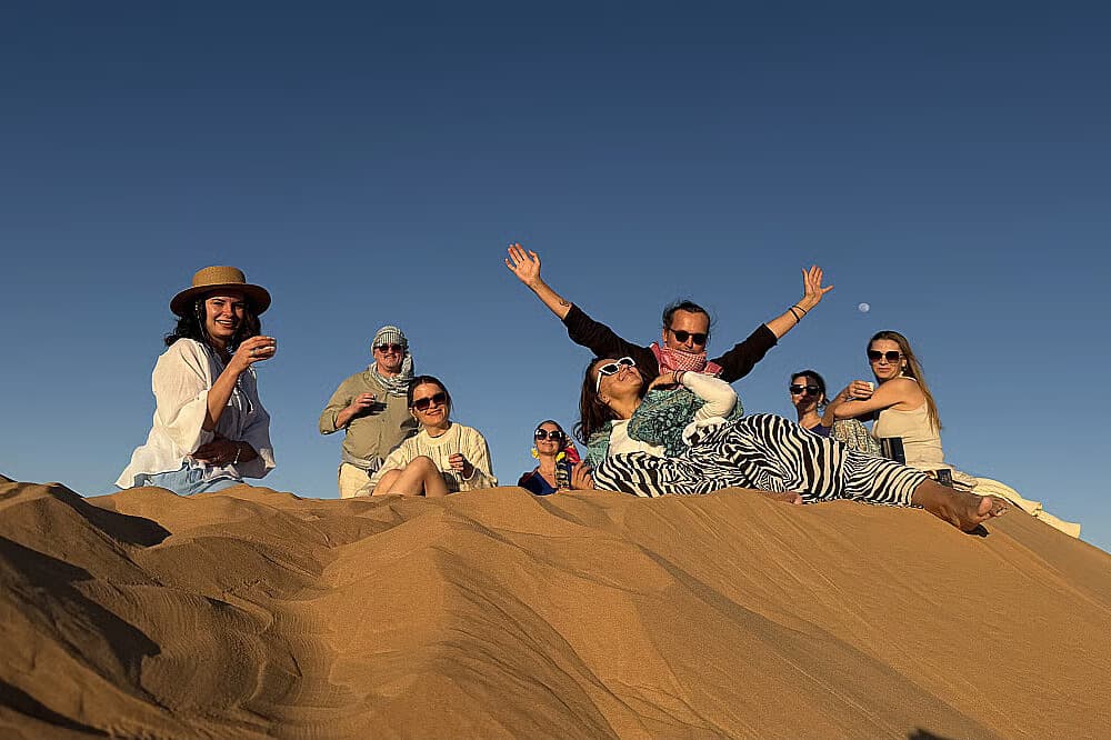 The retreat group gathered along a dune crest against a deep blue sky at golden hour