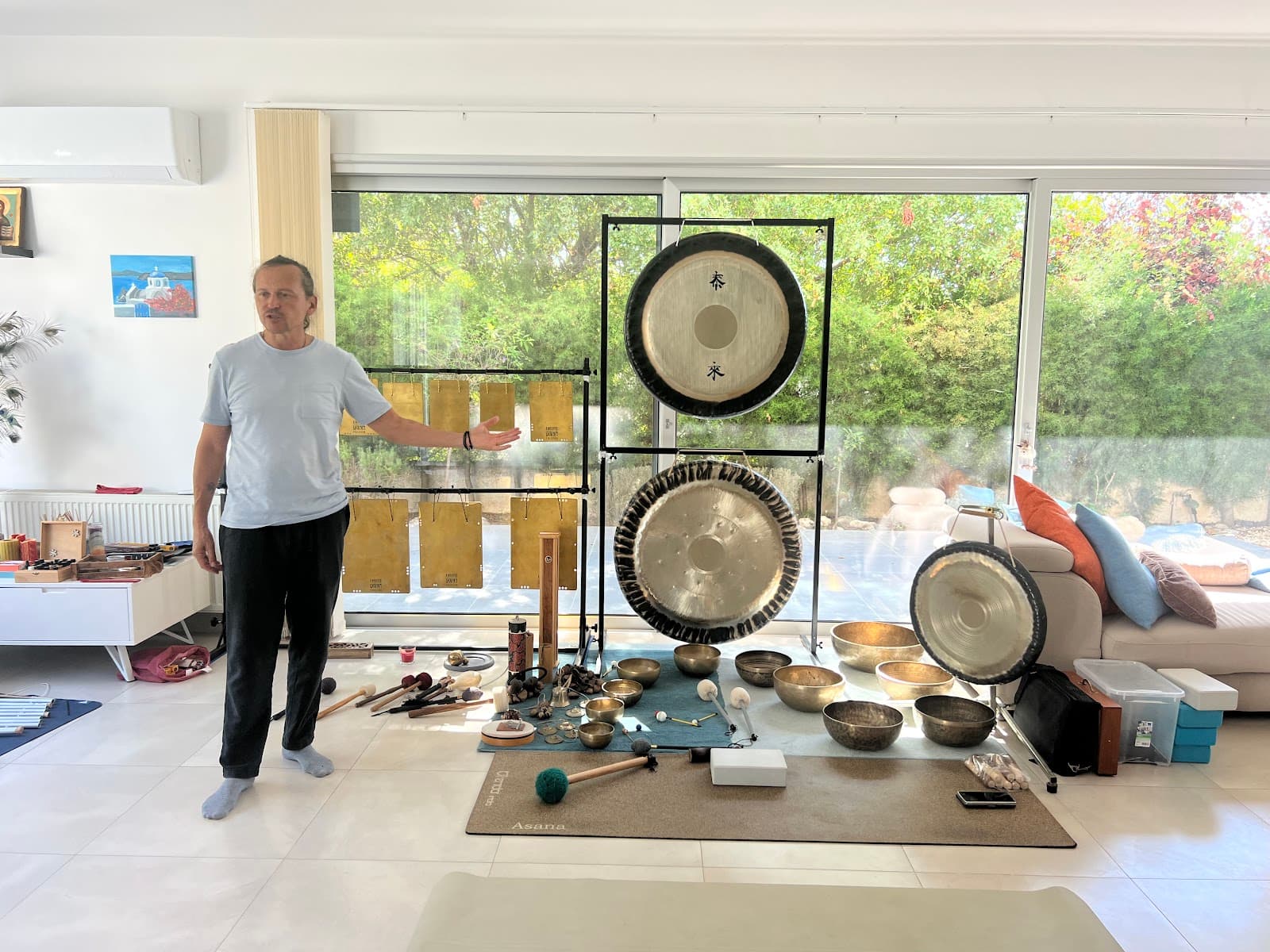 Alexander standing with the gongs, singing bowls and flat bells laid out in the Meditation Hub studio, a photo posted with Karina A.'s review.