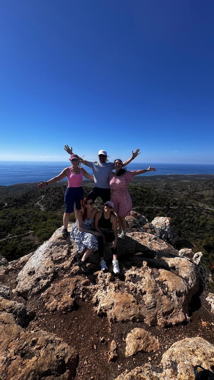 Five retreat guests on a hilltop above the Cyprus coast, arms thrown open, a photo posted with Maria's review.