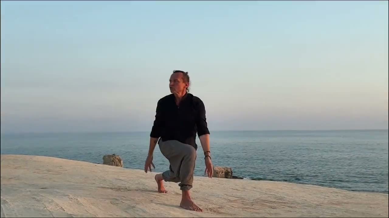 Evening practice standing on pale rock above a calm sea at dusk